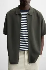 Chaqueta azul marino de tejido con mezcla de algodón, corte relaxed fit, cuello solapa, manga corta y cierre frontal con cremallera.