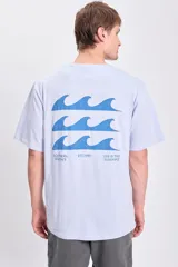 Remera celeste de manga corta con corte oversize y estampa en la espalda con tres olas y texto "Southern Beaches Est.1990 Live in the Sunshine".