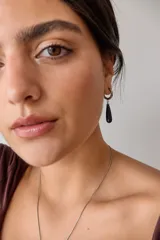 Aros colgantes de acero quirúrgico hipoalergénico con dije de piedra natural en forma de gota color azul oscuro.