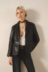Blazer negro de cuero ovino con proceso de lavado que le da un efecto arrugado. Tiene solapas, bolsillos delanteros y forro interior a tono.