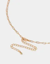 Collar dorado de tres hilos con dijes colgantes: corazón rojo con strass, trébol dorado, herradura dorada con logo de la marca y vaquita de San Antonio celeste con lunares blancos.