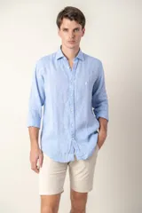 Camisa celeste de lino con cuello clásico y manga larga. Presenta un pequeño logo bordado en el pecho.