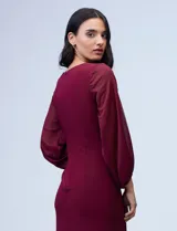 Vestido negro con escote en V y mangas abullonadas, detalle de botones en la cintura.