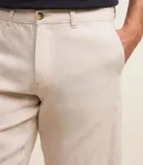 Bermuda de hombre en lino color gris claro, de corte recto, con textura discreta, bolsillos laterales y cierre frontal con botón y cremallera.