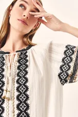 Túnica blanca de algodón con bordados geométricos en negro y dorado en el cuello, el frente y los puños.
