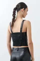 Top negro de cuero sintético con breteles finos y corte ajustado.