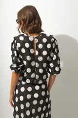 Blusa corta negra con estampado de lunares blancos, escote redondo, mangas abullonadas 3/4 y frunce central.
