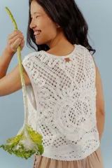 Chaleco blanco de encaje con diseño floral, corte sastrero y sin mangas.