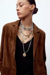 Set de cuatro collares de diferentes largos, con cadenas de eslabones metálicos plateados y dorados. Incluye un choker de eslabones gruesos con medalla central, un collar de eslabones con dijes de medallas labradas, un collar de malla metálica y un collar de eslabones con dije de medalla combinada.