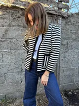 Chaqueta corta de lana merino a rayas horizontales blancas y negras, con cuello redondo y bolsillos frontales.