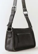 Bolso bandolera de cuero negro con forro interior, asa larga ajustable, hebilla ajustable, detalle metálico y bolsillo exterior con cremallera.