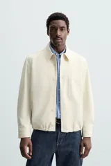 Sobrecamisa color crudo de corte regular fit, confeccionada en tejido con mezcla de viscosa. Tiene cuello solapa, manga larga con puños abotonados, bolsillo de parche en el pecho, bajo ajustable con cordones y cierre frontal con botones.