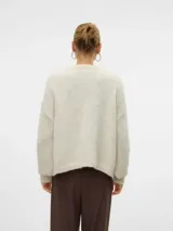 Cardigan de punto color crema, con cuello en V, mangas largas abullonadas, hombros caídos y puños acanalados.