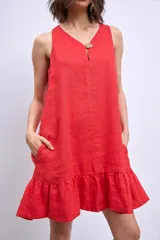 Vestido corto sin mangas, color celeste claro, con escote en V y un pequeño broche decorativo en la abertura frontal. Presenta un corte holgado tipo babydoll con bolsillos laterales y un ruedo con volado.