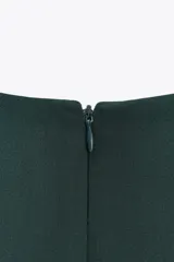 Vestido midi verde oscuro de cuello redondo y sisa americana. Presenta un drapeado en el lateral con detalle de hebilla metálica y abertura en la falda.