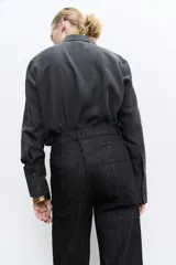 Pantalón de jean negro de tiro alto con trabillas en la cintura, corte bootcut y cinco bolsillos.