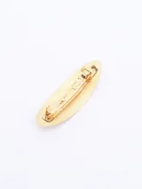 Broche dorado para el pelo con forma ovalada.