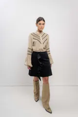 Camisa beige de lino con cuello mao, cierre frontal con botones y detalles de puntilla negra en mangas y frente.