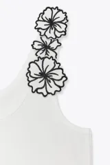 Top blanco de algodón con escote redondo y tirantes decorados con apliques de flores negras.