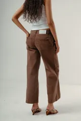 Pantalón de denim color marrón oscuro, tiro medio, con silueta wide leg y costuras verticales marcadas en el frente de ambas piernas.