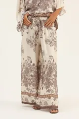 Pantalón palazzo de seda color crema con estampado floral en tonos marrones y cintura elastizada con cordón ajustable.