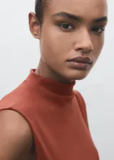 Camiseta sin mangas, ajustada al cuerpo, color terracota/óxido, con cuello perkins y fruncidos laterales.