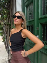 Musculosa negra de un hombro con hebilla carey y frunce en la parte delantera.