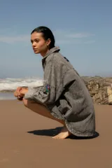 Vestido camisero de denim gris con cuello camisero, cierre frontal con botones, mangas largas con puños abotonados, bolsillos laterales y apliques bordados en el pecho y la manga. Corte holgado y largo a la rodilla.