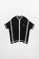 Camisola corta negra de lino con cuello mao, abotonada adelante y rayas blancas en mangas y ruedo.