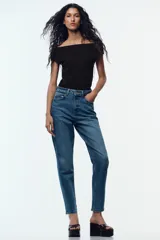 Jeans de tiro alto color celeste, corte mom fit, con cinco bolsillos y cierre frontal con cremallera y botón.