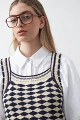 Top tejido sin mangas con diseño geométrico de rombos en relieve, en tonos azul marino y beige. Presenta escote amplio y breteles tejidos.