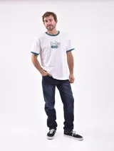 Remera blanca de manga corta con cuello redondo y ribete verde en cuello y mangas. Estampado frontal con texto "Court Classics" y diseño de pelotas de tenis.