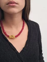 Collar de cuentas rojas con dije de piedra color ámbar.