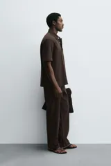 Camisa tipo polo de corte relajado confeccionada en una mezcla de lyocell y algodón. Presenta cuello con solapa, cierre frontal de botones ocultos, manga corta y un bolsillo de parche en el pecho. El bajo cuenta con aberturas laterales.