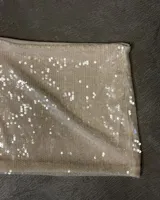 Minifalda tubo color beige claro cubierta de lentejuelas brillantes.