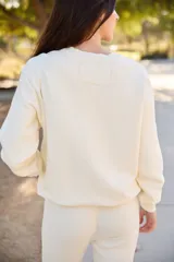 Sweater color crema con cuello redondo y estampado gráfico de montañas y la palabra "COLORADO" en el frente.