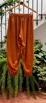 Pantalón tipo babucha color naranja, con cintura y puños elastizados, bolsillos delanteros y confeccionado en algodón.