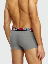Pack de tres bóxers Diesel modelo Damian. El bóxer visible es de color gris melange con elástico negro y rojo que lleva el logo de Diesel repetido en blanco.