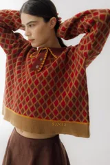 Buzo de lana color beige con diseño de rombos marrones, cuello polo con botones y detalles bordados.