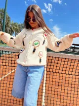 Cardigan tejido a mano en lana merino virgen sin teñir, con bordado de raquetas de pádel y pelotas de colores.