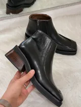 Botas de cuero negras con punta cuadrada, taco bajo de madera y cierre lateral.