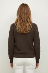 Sweater de punto acrílico color crema, con diseño de trenzas en el cuerpo y mangas, cuello redondo y calce holgado.