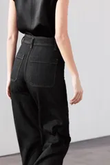 Pantalón de jean celeste de tiro alto y corte wide leg, con bolsillos frontales y traseros, cierre frontal con cremallera y botón metálico.