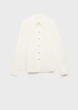 Camisa blanca de tejido fluido, con cuello camisero, cierre frontal con botones y mangas largas con puños abotonados.