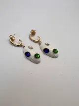 Aros con base de esmalte blanco, adornados con piedras de colores azul y verde sobre un gancho dorado.