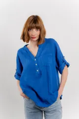 Camisa azul de lino con escote en V abotonado, bolsillo frontal y mangas 3/4 con trabilla.