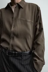 Camisa relaxed fit color verde militar, confeccionada en tejido con mezcla de modal. Tiene cuello solapa, manga larga con puño abotonado, bolsillo plastrón en el pecho y cierre frontal de botonadura.