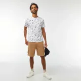 Remera blanca de manga corta con estampado de palmeras y paisajes en azul.