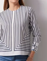Blusa de gasa estampada a rayas verticales blancas y negras, marca Sioni. Espalda con abertura y botón. Manga larga con puño y botón.