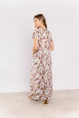 Vestido blanco con estampado de manchas marrones tipo vaca, corte recto y cuello redondo con ribete marrón.